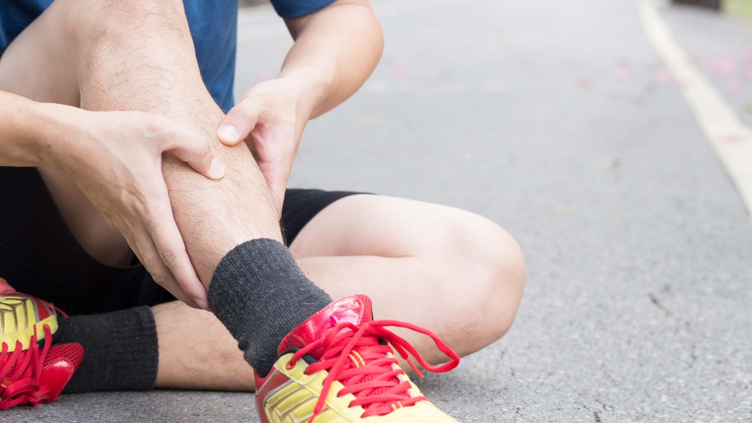 A runner presses into his leg to massage his muscle after a workout.