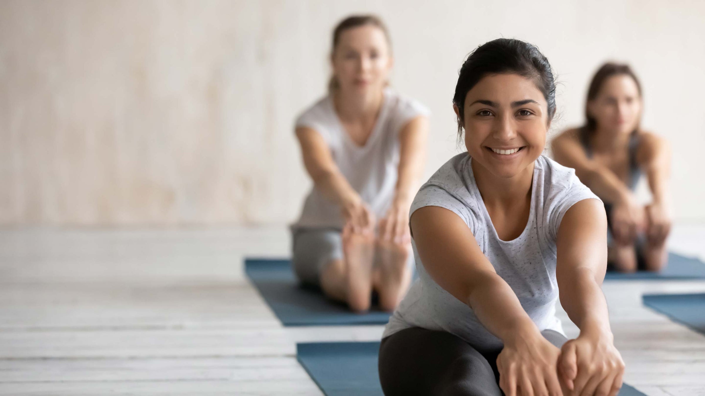 Smiling Indian woman practicing yoga, Seated forward bend exercise.